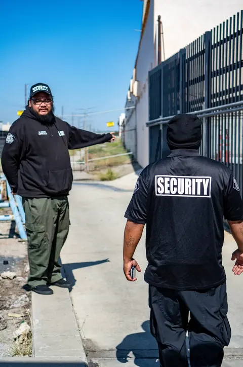 A Galaxy supervisor and an officer walking a fence line at an industrial site